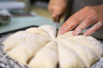 Cutting raw dough in flour with a knife (close-up of hands cutting dough)