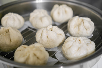 Chinese dumplings (buns) being steamed on a modern stainless steel wok pan