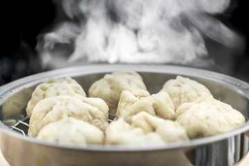 Fototapeta na wymiar Chinese dumplings (buns) being steamed on a modern stainless steel wok pan