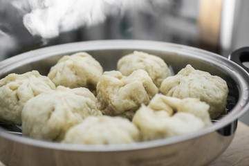 Chinese dumplings (buns) being steamed on a modern stainless steel wok pan