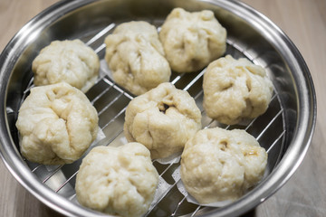 Chinese dumplings (buns) being steamed on a modern stainless steel wok pan
