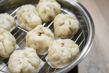 Chinese dumplings (buns) being steamed on a modern stainless steel wok pan