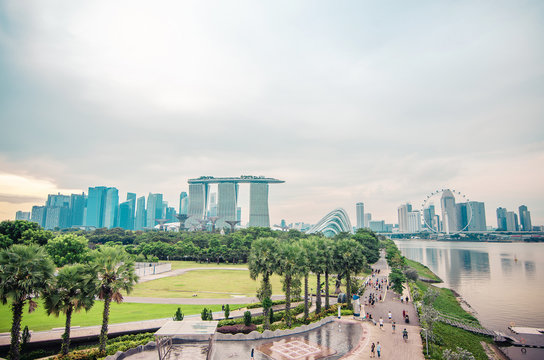 Top View of the Marina Barrage roof top in the evening, Marina Bay Sands, Gardens by the bay with cloud forest, flower dome and supertrees at sunset timelapse.