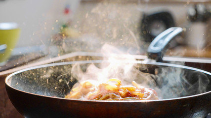 Cook put basil leafs on spaghetti with red tomato sauce in the frying pan