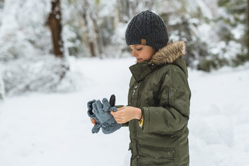 Fototapeta na wymiar cute little boy putting winter glows outdoor