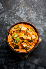 Malai or achari Paneer in a gravy made using red gravy and green capsicum. served in a bowl. selective focus