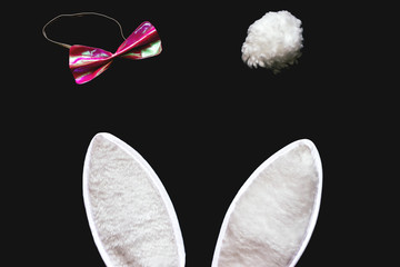 White rabbit ears and pink bow on black background.
