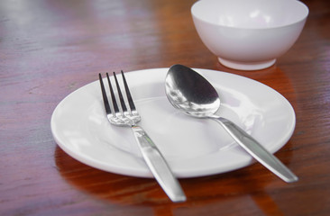 The empty plate has a white color placed on the table for putting rice