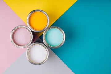 Vier offene Farbdosen auf hellem Symmetriehintergrund. Gelbe, weiße, rosa, türkisfarbene Farben. Platz für Text. Renovierungskonzept. © Anna Efetova