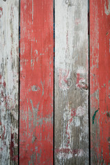 Rustic wood background with peeling red and white painted stripes in a full frame close-up abstract background