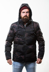 Comfortable winter outfit. Winter stylish menswear. Man bearded stand warm camouflage pattern jacket parka isolated on white background. Hipster winter fashion. Guy wear hat and black winter jacket