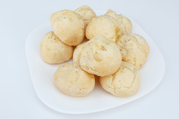 Brazilian breakfast, cheese bread (pao de queijo) served on dish on white table.
