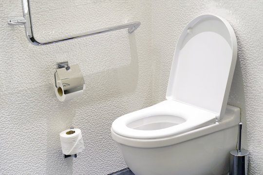 Close-up of toilet bowl and roll on toilet paper holder. Toilet paper roll in restroom. Public toilet in the airport or restaurant, cafe.