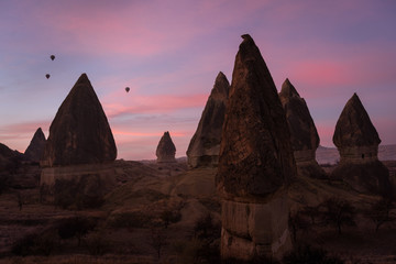 magnificent rocks in Capadocia at sunrice with some hot air baloons