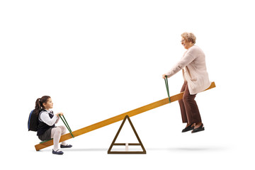 Little schoolgirl and an elderly woman playing on a seesaw