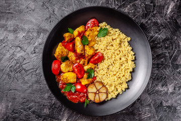 Mexican cuisine. Rice with black sesame. Spicy chicken with curry, paprika, cherry tomatoes and honest. Red Salsa Sauce Serve in a black plate, near spices. Recipe Background Image