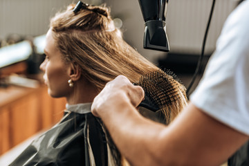 Fototapeta premium cropped shot of hairdresser drying hair to attractive girl in beauty salon