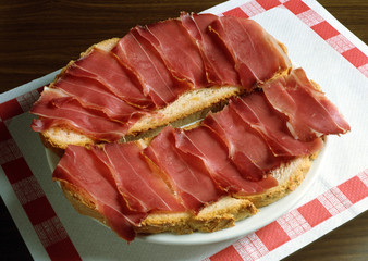 Plato con dos rebanadas de pan con jamón curado.