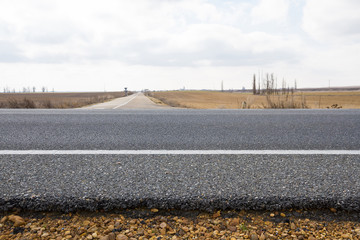 Vista transversal de la capa de base asfaltica o  firme con graba y asfalto de una carretera a ras del suelo en el cruce con otra 