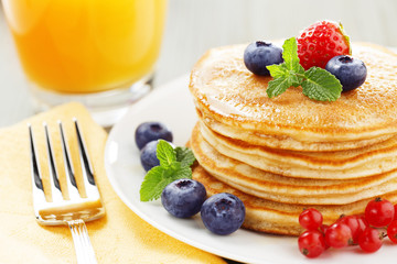 stack of pancakes with berries and orange juice