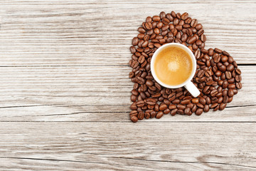 coffee cup in a heart of beans on wooden table