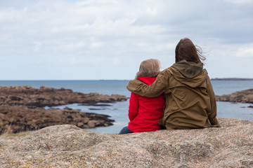 the sisters are sitting on the shore of the ocean