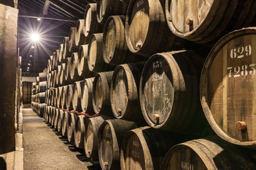 Row of wooden porto wine barrels in wine cellar Porto, Portugal.