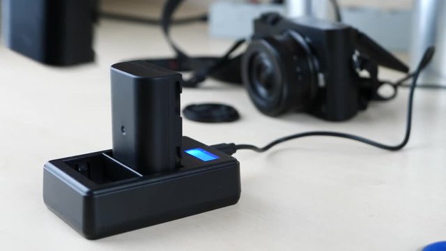 Charging black battery for phoro camera on wooden table