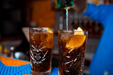 Barmen hand with shaker  pouring cocktail into glass, on bright background