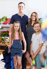 Smiling family with kids standing near fresh fruits  and vegetables i