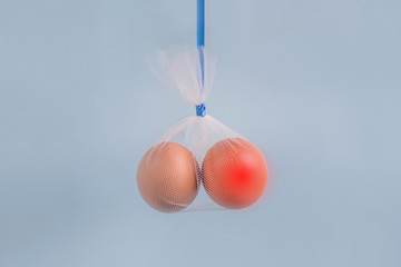 Testicular cancer concept: eggs in a tulle bag on a blue background one egg red