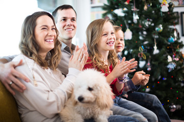 Young positive family enjoying Christmas evening at home