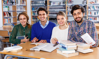 Fototapeta na wymiar Group portrait of smiling young adults engaged in research, working together in public library