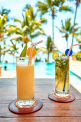 Summer hat, a cocktail and sunglasses near the luxurious pool.
