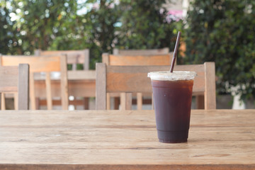 Americano iced coffee in takeaway plastic cup on wooden desk in coffee's shop