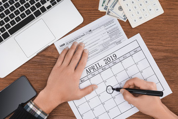 cropped view of man marking april 17 date in calendar on wooden desk