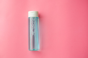 bottle with tonic or micellar cleansing water with fresh herbs and flowers on pink background, top view. Beauty, skin, hair or body care concept. selective focus