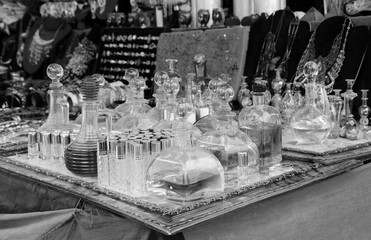 Vintage perfume bottles at flea market in Portugal. Aged photo. Black and white.
