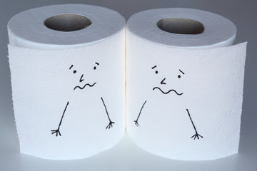Two white toilet paper rolls sketched with frightened characters close to each others, with a scared face, representing the fear feelings