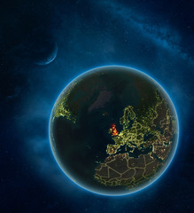 United Kingdom at night from space with Moon and Milky Way. Detailed planet Earth with city lights and visible country borders.