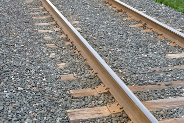 Naklejka premium A Railway Track Made Of Metal And Wood. Rocks And Stones Are Used As A Ballast To Help Hinder Growth Of Plants And Keep A Stable Foundation For The Tracks. 