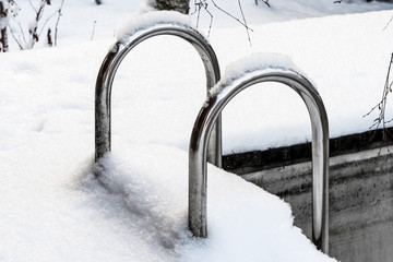 metal staircase in the outdoor pool covered by snow