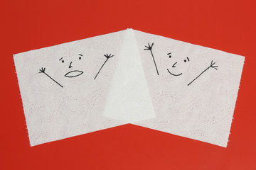 Two white toilet paper pieces sketched with a shouting and a cheerful face close to each other, representing the panic and the happiness feelings