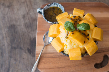 Refreshing mango ice cream and passion fruit in ceramic bowl on wooden desk for favorite summer dessert