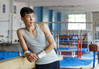 Positive young man asian acrobat posing  at modern sport gym