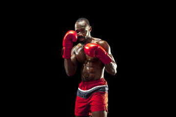 Hands of boxer over black background. Strength, attack and motion concept. Fit african american model in movement. Afro muscular athlete in sport uniform. Sporty man during boxing