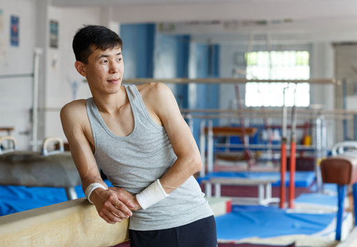 Positive young man asian acrobat posing  at modern sport gym