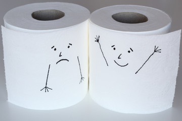 Two white toilet paper rolls sketched with a sad and a cheerful face, close to each others, representing the sadness and the happiness feelings