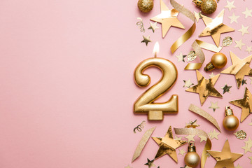 Number 2 gold celebration candle on star and glitter background