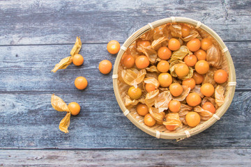 Cape gooseberry fruits in the basket (Physalis peruviana) on wooden background.Commonly called goldenberry, golden berry, Pichuberry.